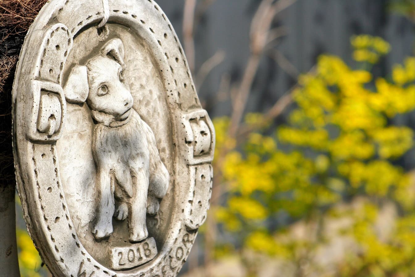 昼間の庭に置かれている犬の絵が入った置物