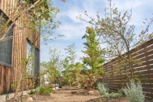 緑の植物と木製のフェンス、木の壁が印象的なお家の庭