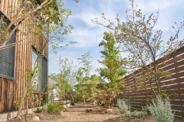 緑の植物と木製のフェンス、木の壁が印象的なお家の庭