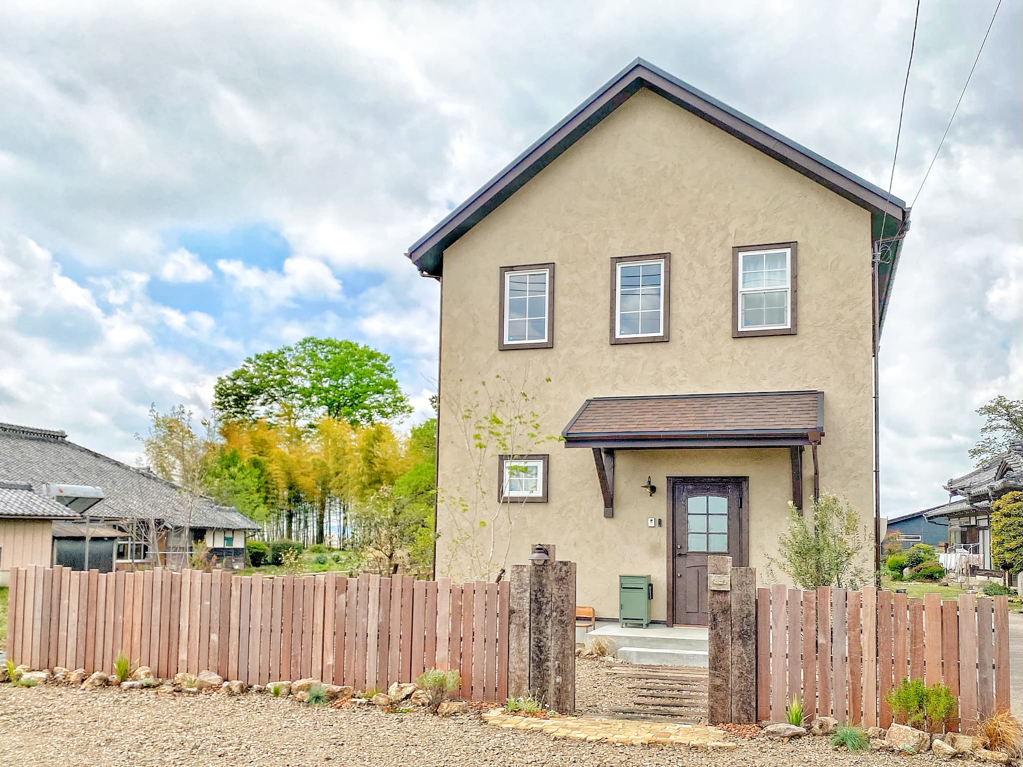 ベージュの壁と木製のフェンスが印象的な家