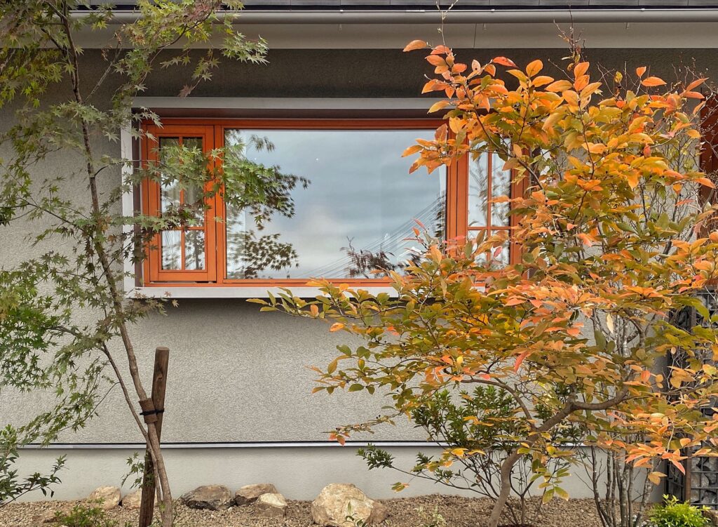 オレンジ色の窓枠が印象的な秋の庭